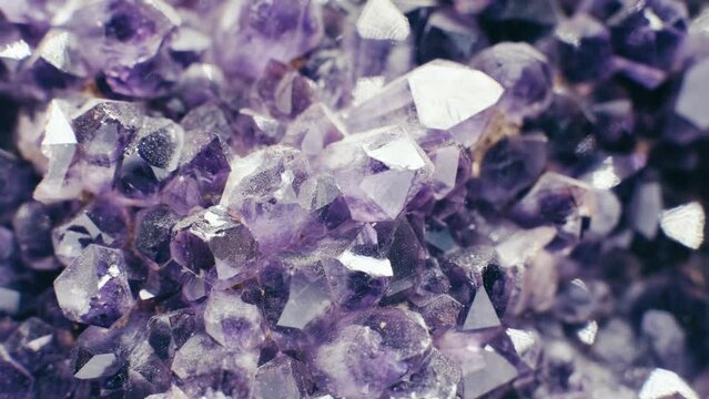 Footage of amazing flashing Violet Crystal cluster close up. Shiny Purple rough Amethyst quartz crystals geode. Macro of beautiful rare sparkling mineral stone.4K