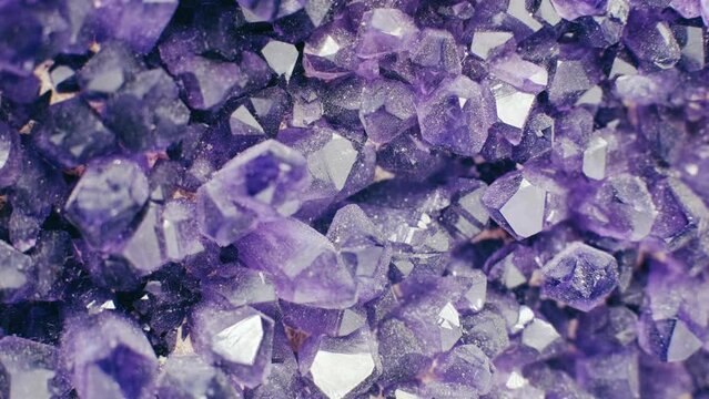 Footage of amazing flashing Violet Crystal cluster close up. Shiny Purple rough Amethyst quartz crystals geode. Macro of beautiful rare sparkling mineral stone. 4K . 1