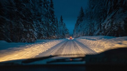 Lonely straight road through forest in sweden, dangerous snow and ice on the road at freezing...