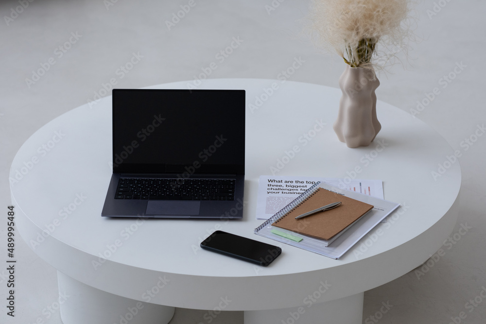 Poster small minimal round table of white color with laptop, mobile phone, notebook, papers and vase with d