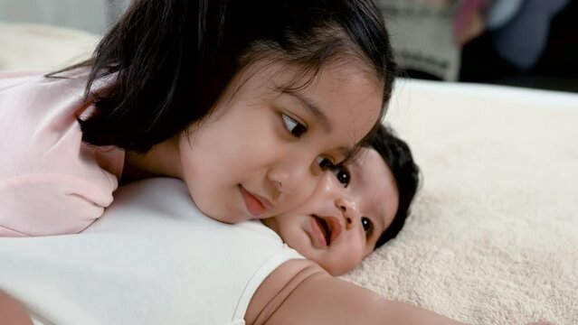 4K, 50 fsp aborable gril , playing with baby boy in bed in bedroom,warm and happy expression.