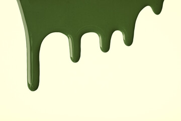 Dark green liquid drops of paint color flow down on light olive background. Abstract khaki backdrop