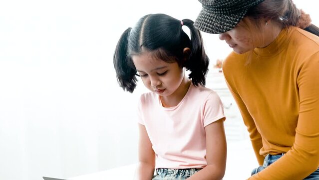 4K, 50 fsp Two young Asian girls sit on the bed in the bedroom, sister teaching sister to play laptop computer.