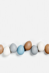 Painted Easter eggs blue, gray, beige colored in row on white background with copy space. Chicken egg natural pastel shades. Easter holiday food, minimal design aesthetic flat lay