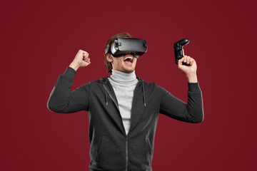 Joyful man in VR headset celebrating victory in videogame