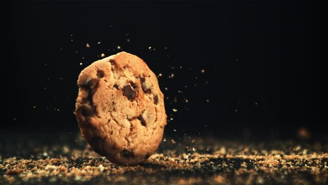 Cookies with pieces of chocolate fall on the table. On a black background. Filmed on a high-speed camera at 1000 fps. High quality FullHD footage