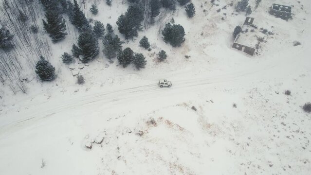 Drone Aerial View of Land Rover Defender D90 SUV Parked on Snowy Backcountry Alpine Forest Road in Rocky Mountains near Nederland Boulder Colorado USA During Heavy Snowfall.