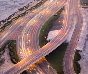 Aerial view of a multi level road crossing during evening hour with trails of traffic lights.