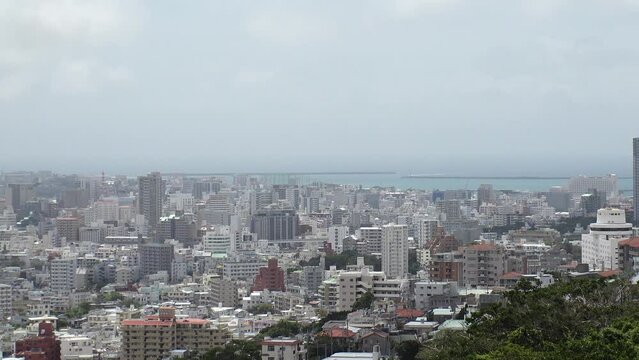 NAHA, OKINAWA, JAPAN - AUGUST 2021 : Aerial high angle view of Naha city. Cityscape of downtown area and sunny blue sky. Time lapse shot in daytime. Summer holiday, vacation and travel concept video.