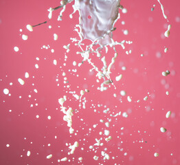 Splashes of white milk on a pink background.