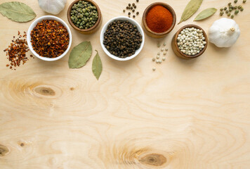 Different types of peppers in small bowls on wooden background, space for text