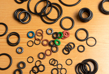 Black hydraulic and pneumatic o-rings in different sizes on a wooden background. Sealing rings for hydraulic connections. Rubber seals for plumbing.
