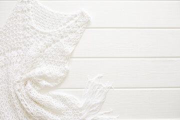 A white knitted dress lies on a white wooden deck chair. Swimwear, leisure wear. Vacation concept...