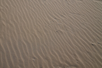 Fototapeta na wymiar Fine wave beach sand in summer sun Brown sandy background
