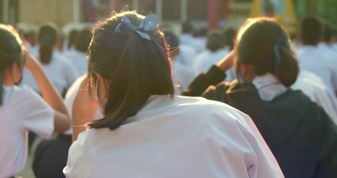 Slow motion scene in the morning while the Asian high school students in white uniform wearing the masks sit in line during the Coronavirus 2019 (Covid-19) epidemic.