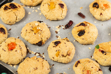 Refrigeration of freshly baked soft oatmeal cookies with raisins, candied fruits, flax and sesame seeds and walnuts on baking paper