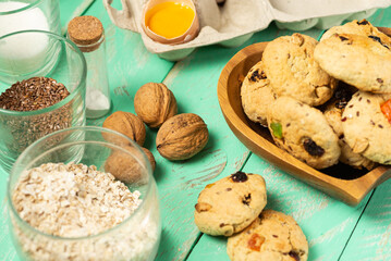 Cooking oatmeal cookies with candied fruits and walnuts. Eggs, oatmeal, flour, sugar, spices and kitchen utensils on an old wood. Baking recipe or classroom mockup, pastry making concept