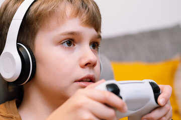 Portrait of concentrated teen boy with a joystick in his hands playing the console.
