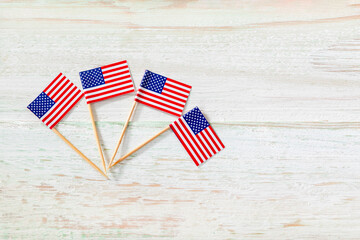 Closeup studio top view shot of four small miniature paper pride American USA United States of America country national toothpick stick flags placed on old vintage wooden background with copy space