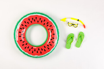 Studio top view shot two pairs of green rubber casual slippers with snorkel, watermelon swimming pool ring for summer beach sea weekend vacation on white background