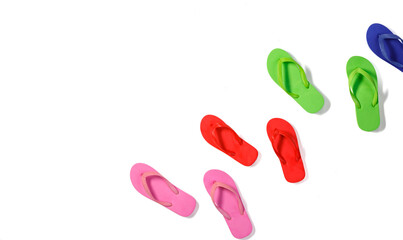 Studio top view shot four pairs of colorful pink red green and blue rubber casual unisex slippers flip flops sandals footwear for summer beach sea weekend vacation on white background with copy space