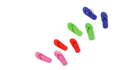 Studio top view shot four pairs of colorful pink red green and blue rubber casual unisex slippers flip flops sandals footwear for summer beach sea weekend vacation on white background with copy space