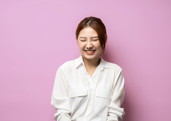 Fototapeta premium Portrait of happy and positive woman close eyes, smiling carefree, standing in shirt on pink background.