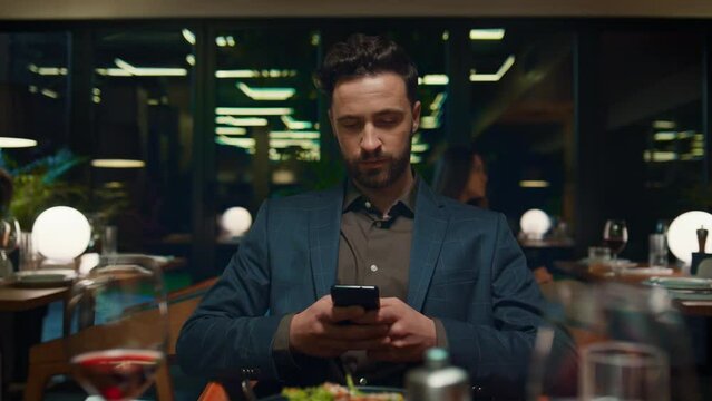Focused businessman sitting restaurant. Respectable man texting mobile phone.