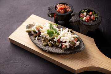 Tlacoyo with sNopales. Mexican pre hispanic dish made of blue corn flour patty filled with refried beans. Popular street food in Mexico.