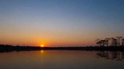 sunrise at coast of the lake. Blue sky and sun reflection on water. Nature landscape in asian.