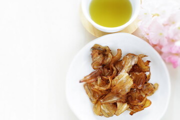 Japanese snack food, dried fish on plate and green tea with copy space