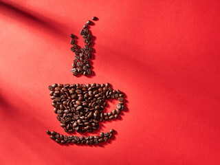 Coffee cup shape made with coffee beans idea, on red background..