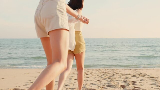 Happy friends holding hands running enjoy life funny and freedom on sand at beach together to sea in holiday vacation time at sunset, Young Asian group woman and man in summer travel, people lifestyle