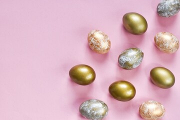 Elegant golden and white Easter eggs painted with dots and stripes on pink background. Copy space, flat lay composition. Happy easter. Greeting card for holiday