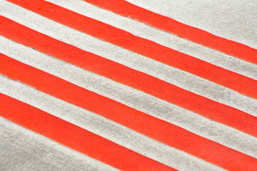 Red stripes diagonally on a gray background. Roadway markings. Crosswalk lanes close up.