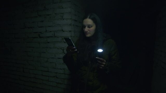 a girl in a terrible state searches a scary basement to find a possible shelter in case of a bomb explosion. News about tensions between Ukraine and Russia. Russian aggression. The threat of war.