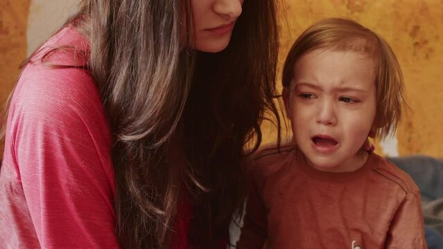 Krivoy Rog, UKRAINE - FEBRUARY 2022 a sad girl looks at the terrible news on the smartphone about the Russian offensive on the territory of Ukraine. a small child cries next to his mother because of