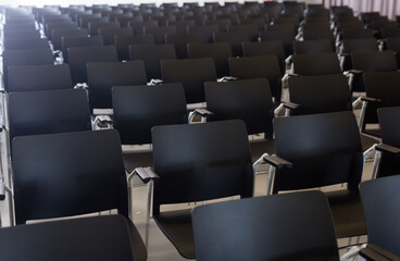 Rows of black plastic chairs in conference hall