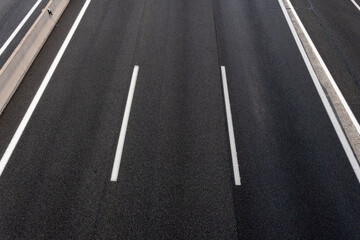 Road background composed of several lanes in an abstract way. Dark three lane highway with white...