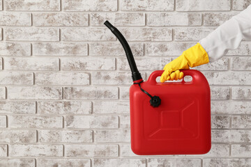 Male hand in rubber gloves holding canister near brick wall
