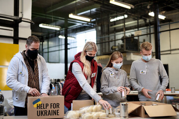 Volunteers sorting out donated food for the needs of Ukrainian migrants, humanitarian aid concept.