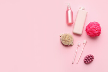 Bottles of cosmetic products and bath accessories on pink background