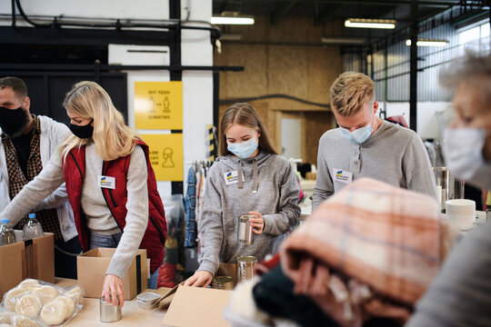 Volunteers sorting out donated food and clothes for the needs of Ukrainian migrants, humanitarian aid concept.