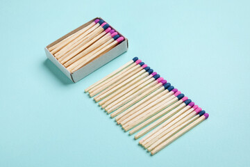 Box with different new matchsticks on blue background