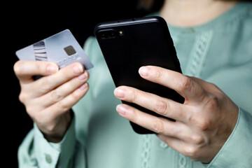 Woman holding smartphone and credit card in hands. Concept of online shopping and payments, blocking transactions