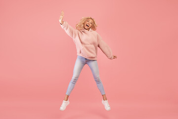 Expressing joy and happiness. Full length shot of active young woman jumping and having fun over...