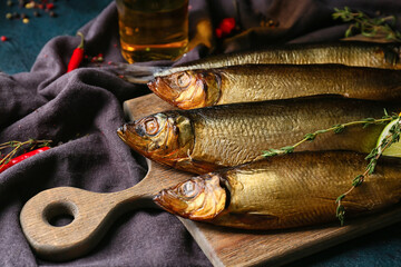 Wooden board with smoked herring fishes on table, closeup