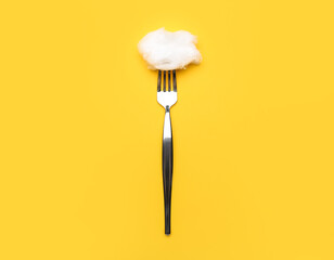 Fork with cotton wool on yellow background