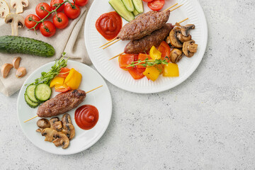 Plates of skewers with tasty lula kebab and vegetables on light background