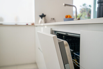 Open White Automatic Dishwasher, Close-Up in a modern, blurred kitchen